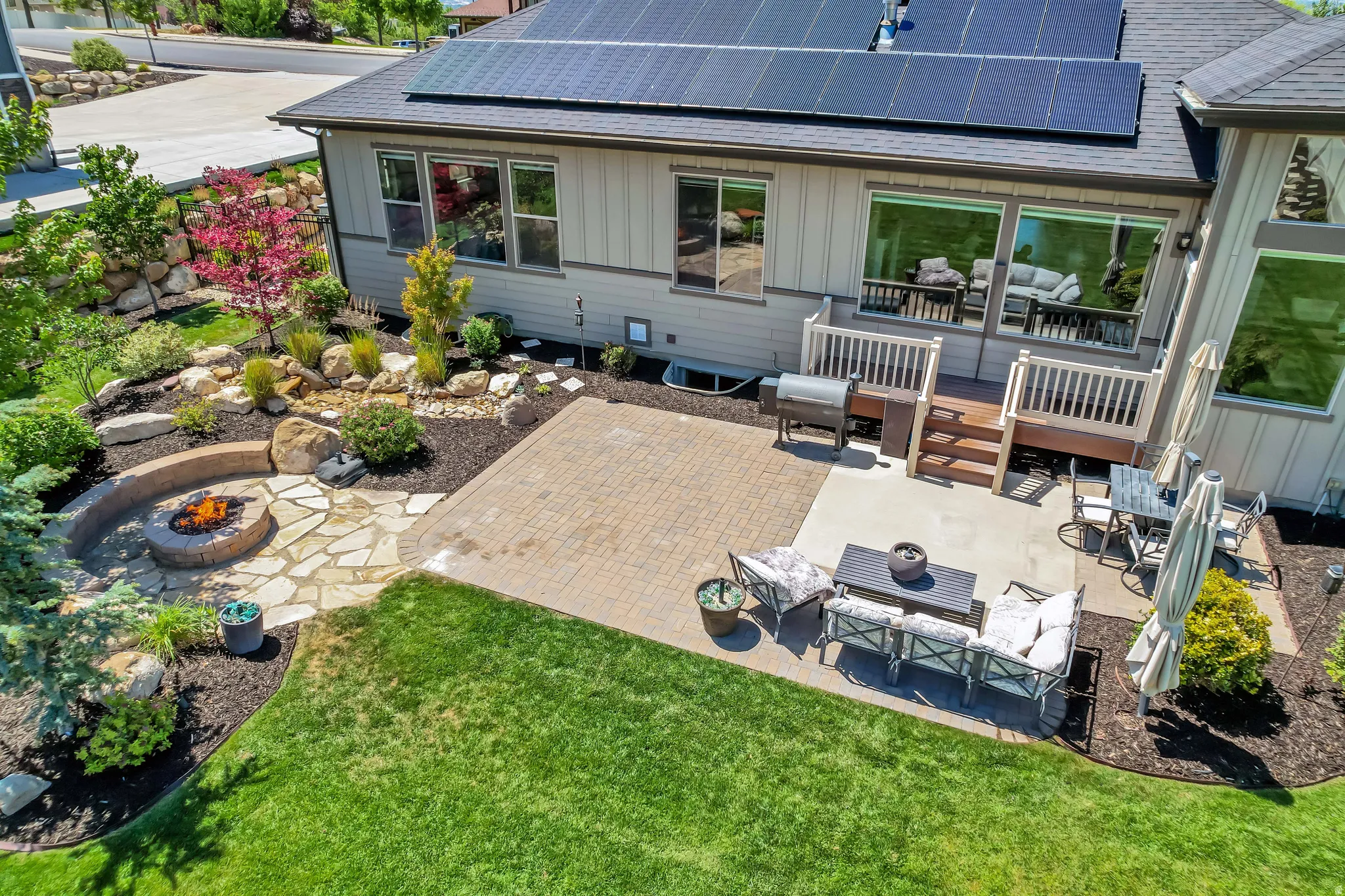 Expansive backyard featuring a stone fire pit, paver patio, multi-level deck, and mature landscaping