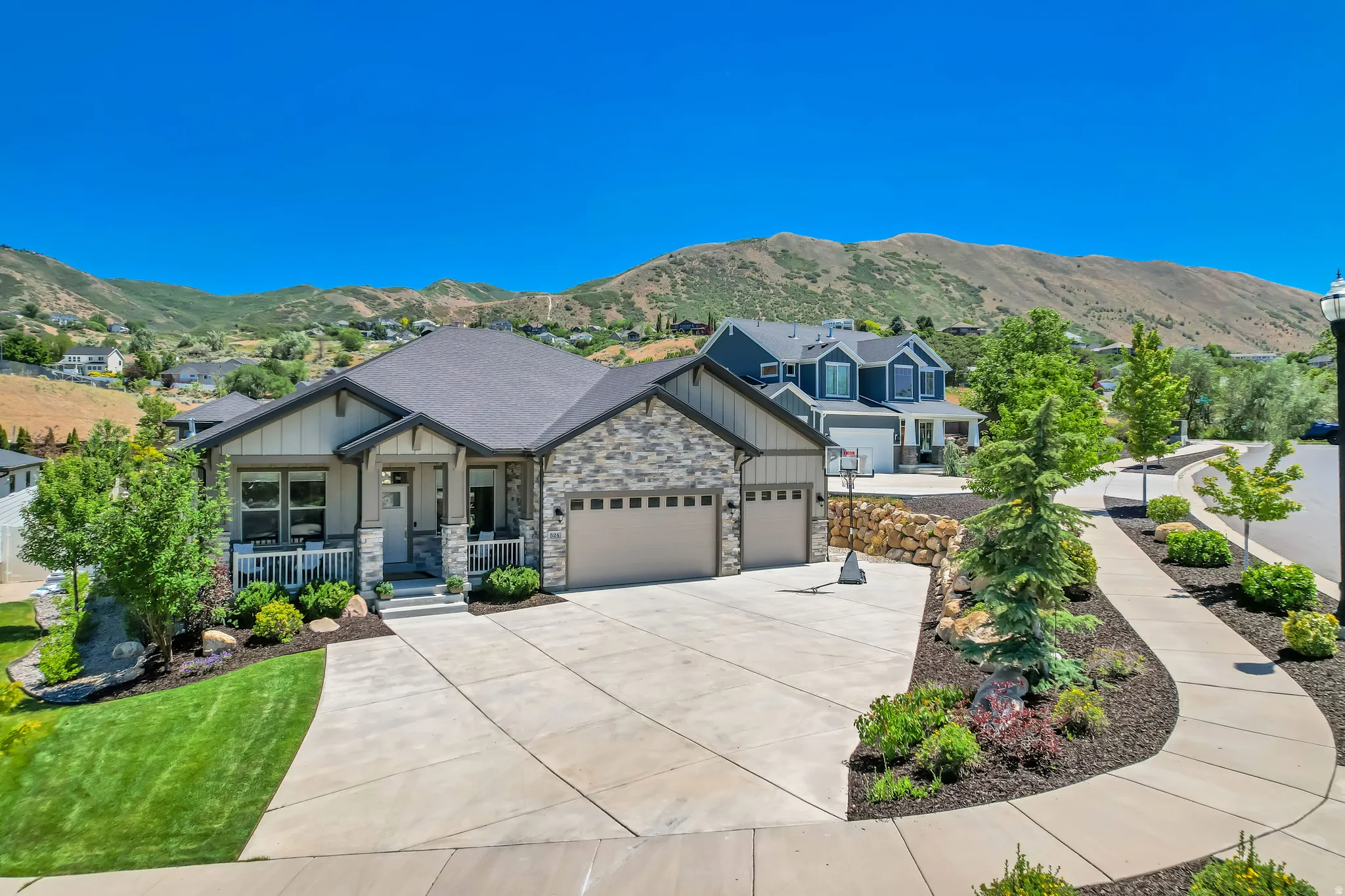 Single-story home featuring a stone and siding exterior, an attached multi-car garage, and a covered front porch