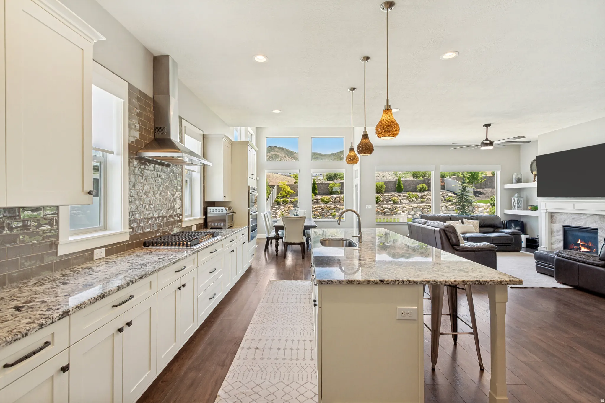 Spacious open-concept kitchen featuring white cabinetry, granite countertops, a tiled backsplash, and stainless steel appliances