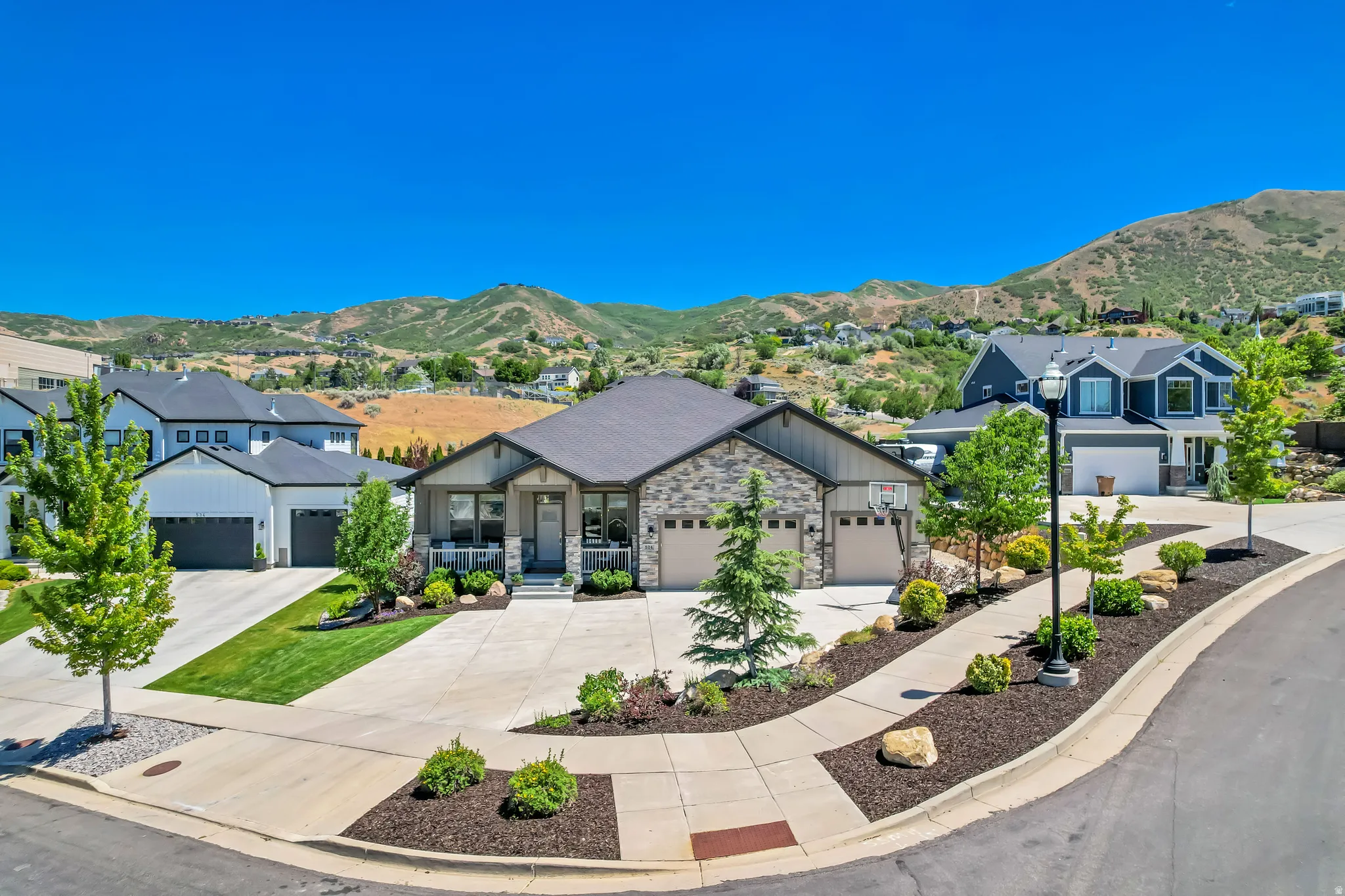 Contemporary residence featuring a stone and siding exterior, an attached multi-car garage, and a covered front porch