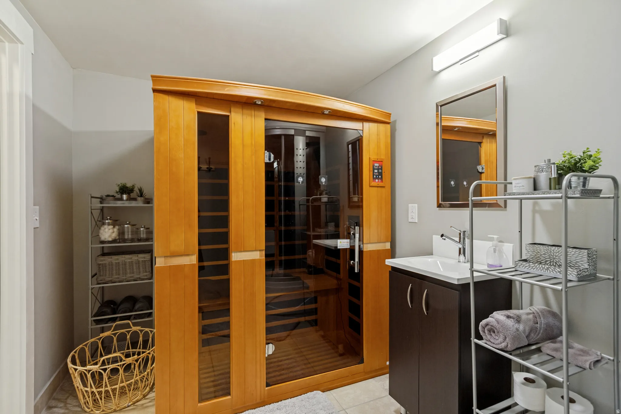 Built-in sauna with wood and glass construction, complemented by a modern vanity featuring a rectangular sink and dark cabinetry