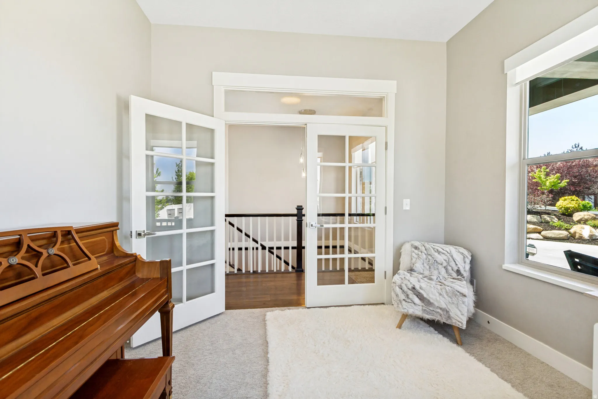 Double French doors opening to an upper-level landing with dark wood-finish flooring and white balusters