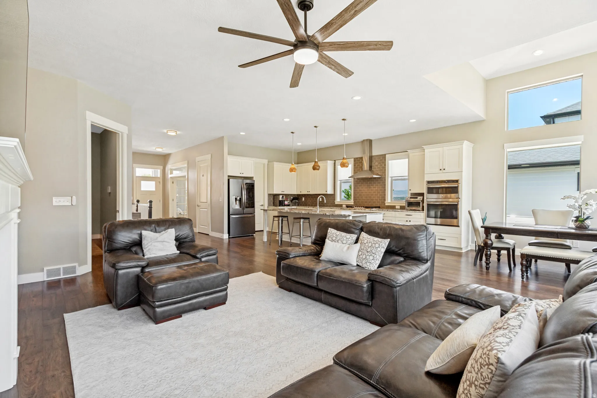 Open-concept living area featuring rich wood-finish flooring, a contemporary ceiling fan, and recessed lighting