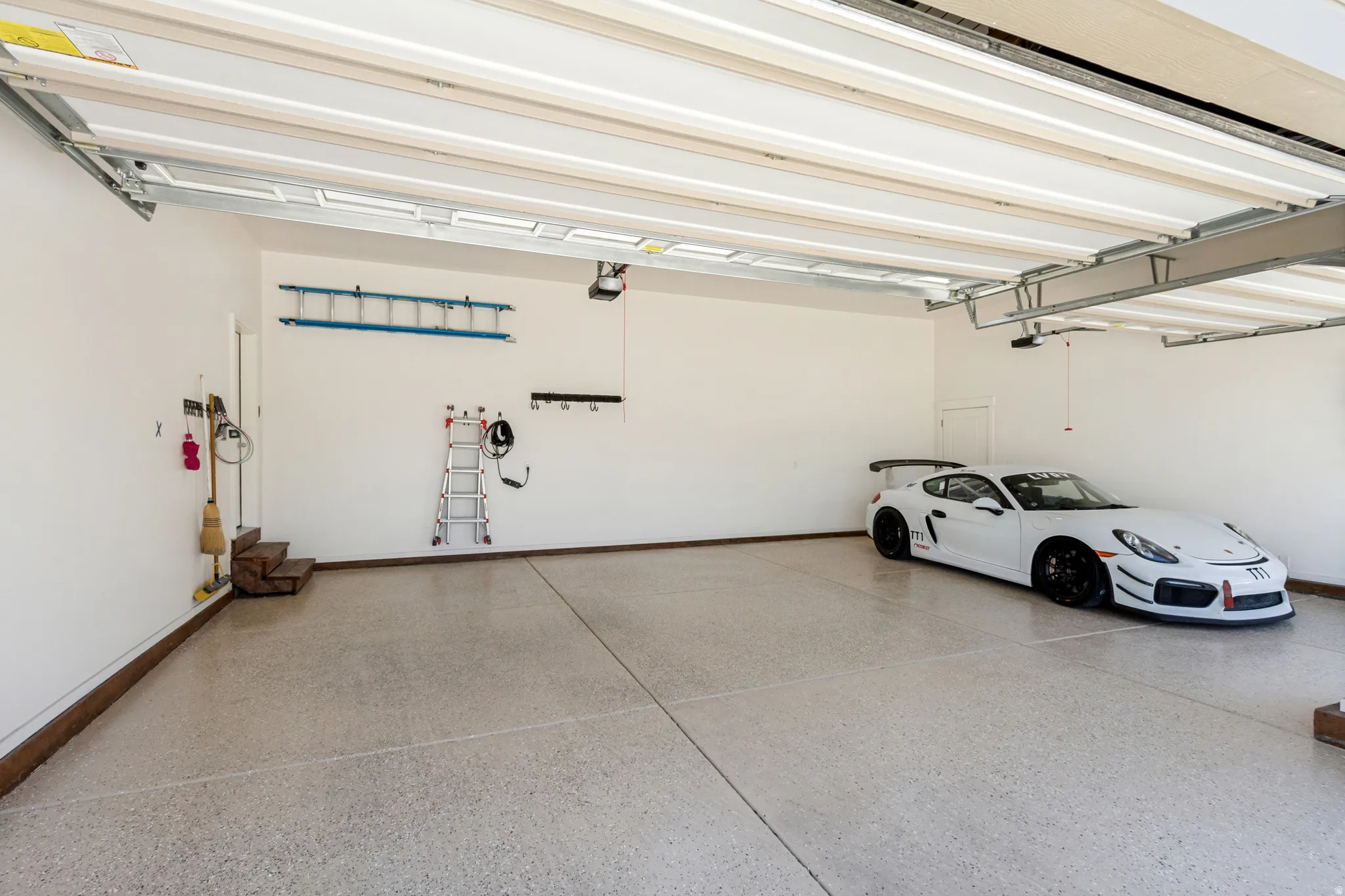 Spacious garage with light-colored epoxy flooring, white walls, and a large overhead door