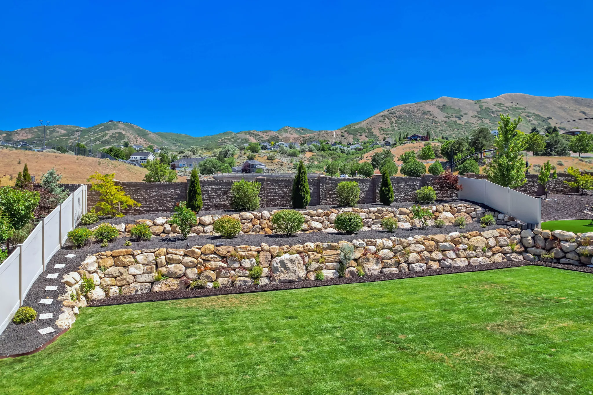 Expansive terraced backyard featuring a vibrant green lawn