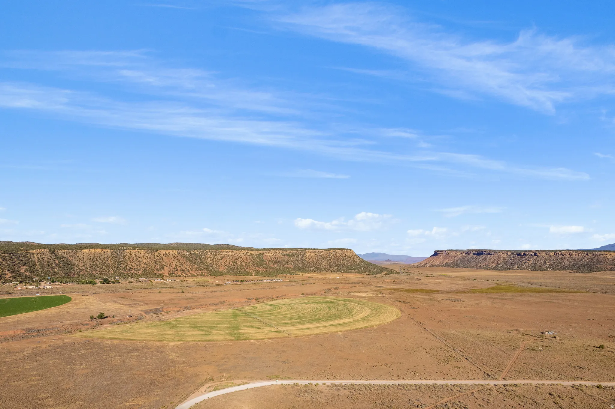 Expansive land parcel featuring natural mesa formations and a large cultivated field