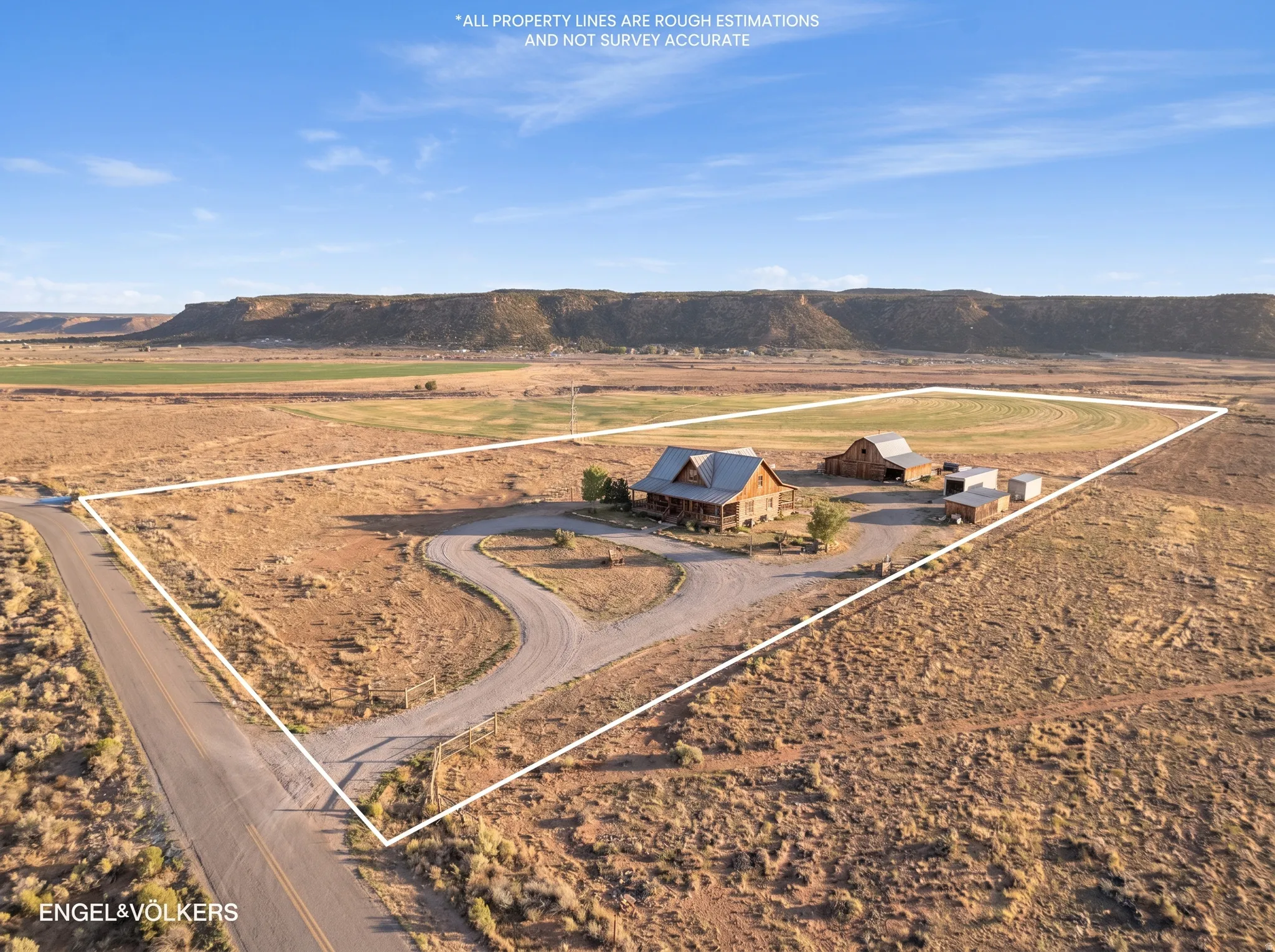 Expansive property featuring a log cabin style home with a covered front porch, a barn, and multiple outbuildings