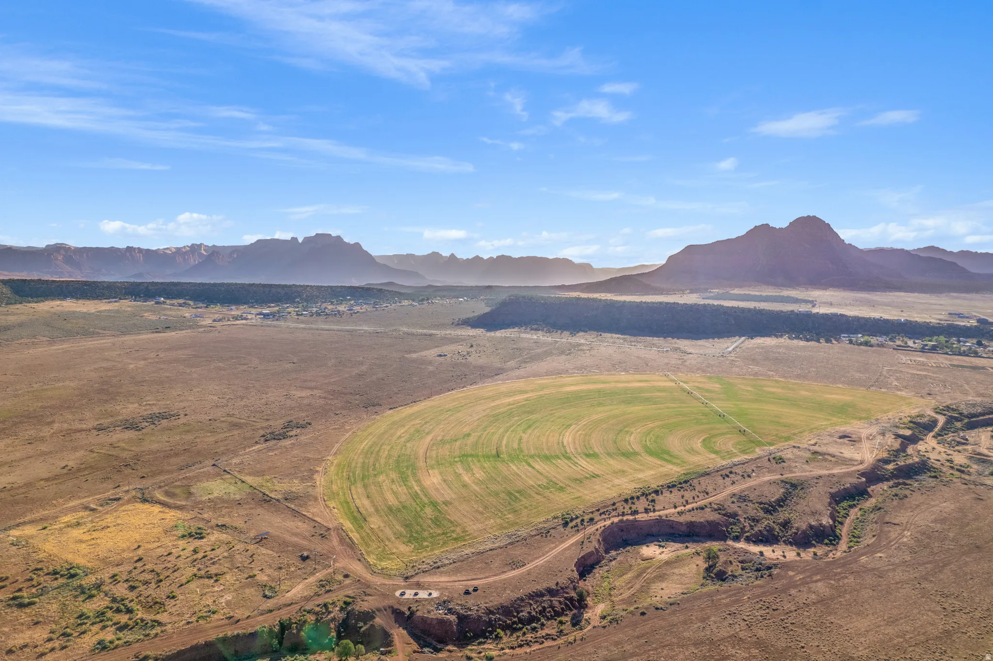 Expansive land featuring a large circular cultivated field, a smaller rectangular cultivated area, and a natural ravine