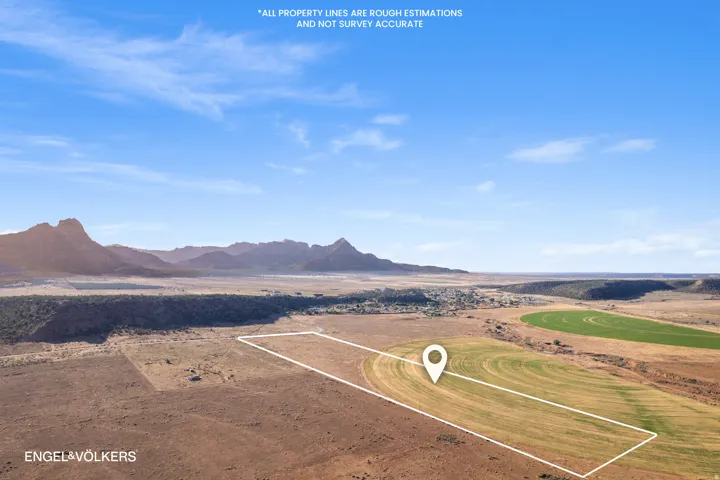 Expansive land parcel featuring agricultural fields, surrounding arid terrain, and distant mountains under a clear sky