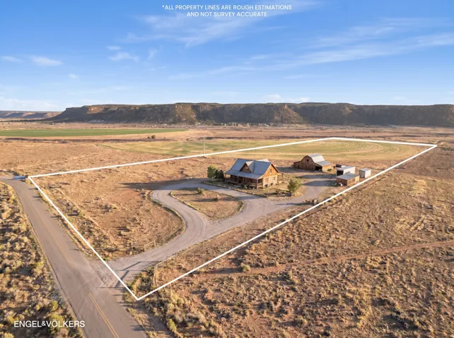 Expansive property featuring a log cabin style home with a covered front porch, a barn, and multiple outbuildings