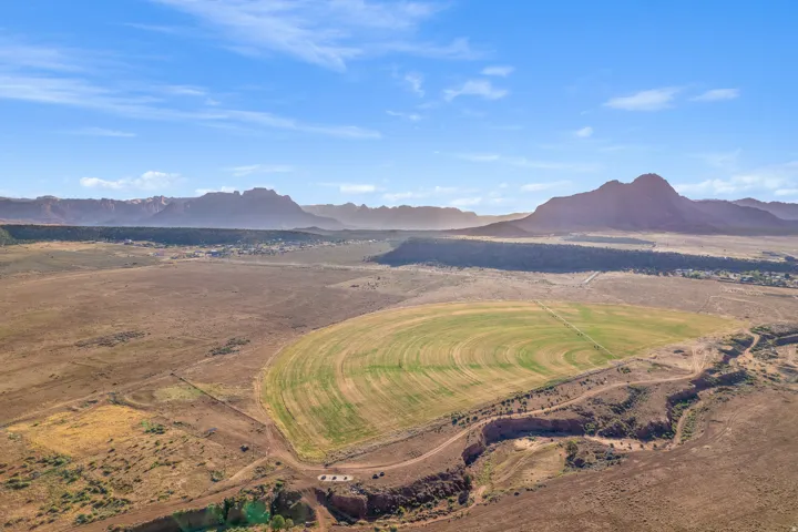 Expansive land featuring a large circular cultivated field, a smaller rectangular cultivated area, and a natural ravine