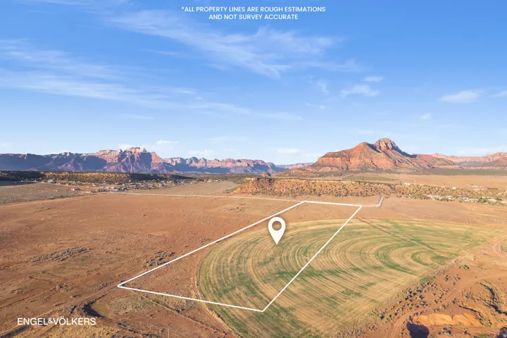 Expansive land parcel featuring partial cultivation, arid landscape, and distant mountain ranges under a clear sky