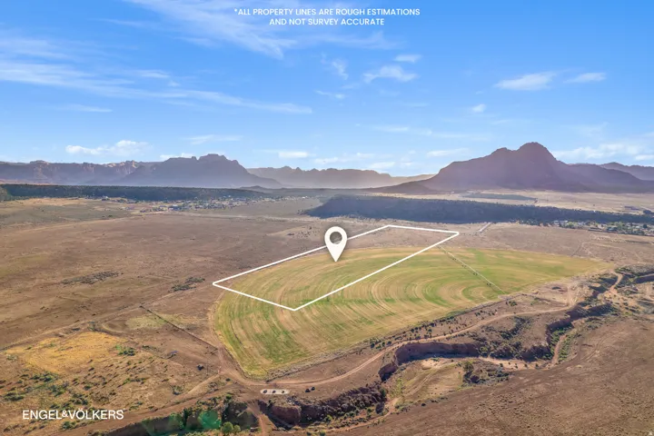Expansive acreage featuring cultivated fields, surrounding natural terrain, and distant mountain ranges under a clear sky