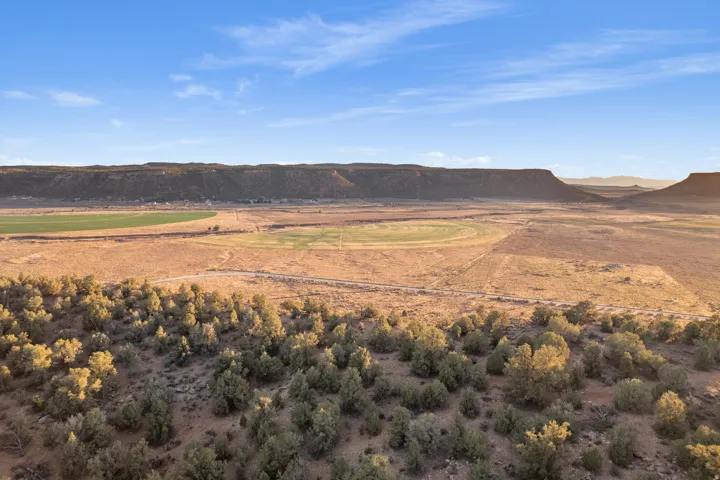 Expansive desert landscape featuring natural scrub brush and distant mesa formations