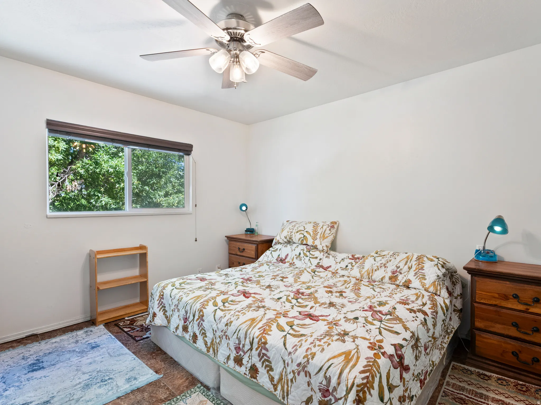 Interior room featuring a ceiling fan with integrated lighting, a window with a dark wood-finish valance, and neutral wall tones
