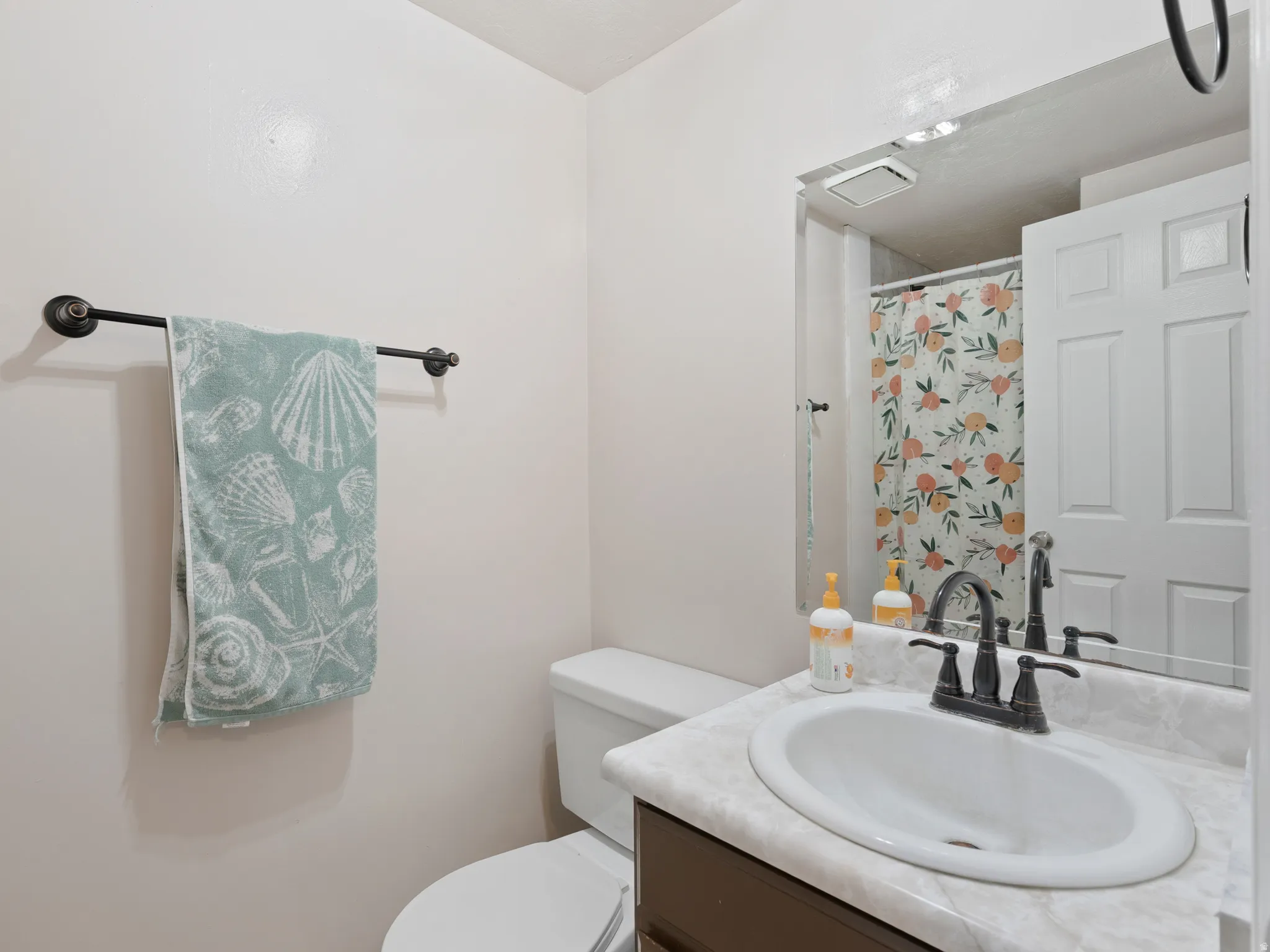 Bathroom featuring a dark wood vanity with a white countertop and an oval undermount sink, complemented by an oil-rubbed bronze faucet