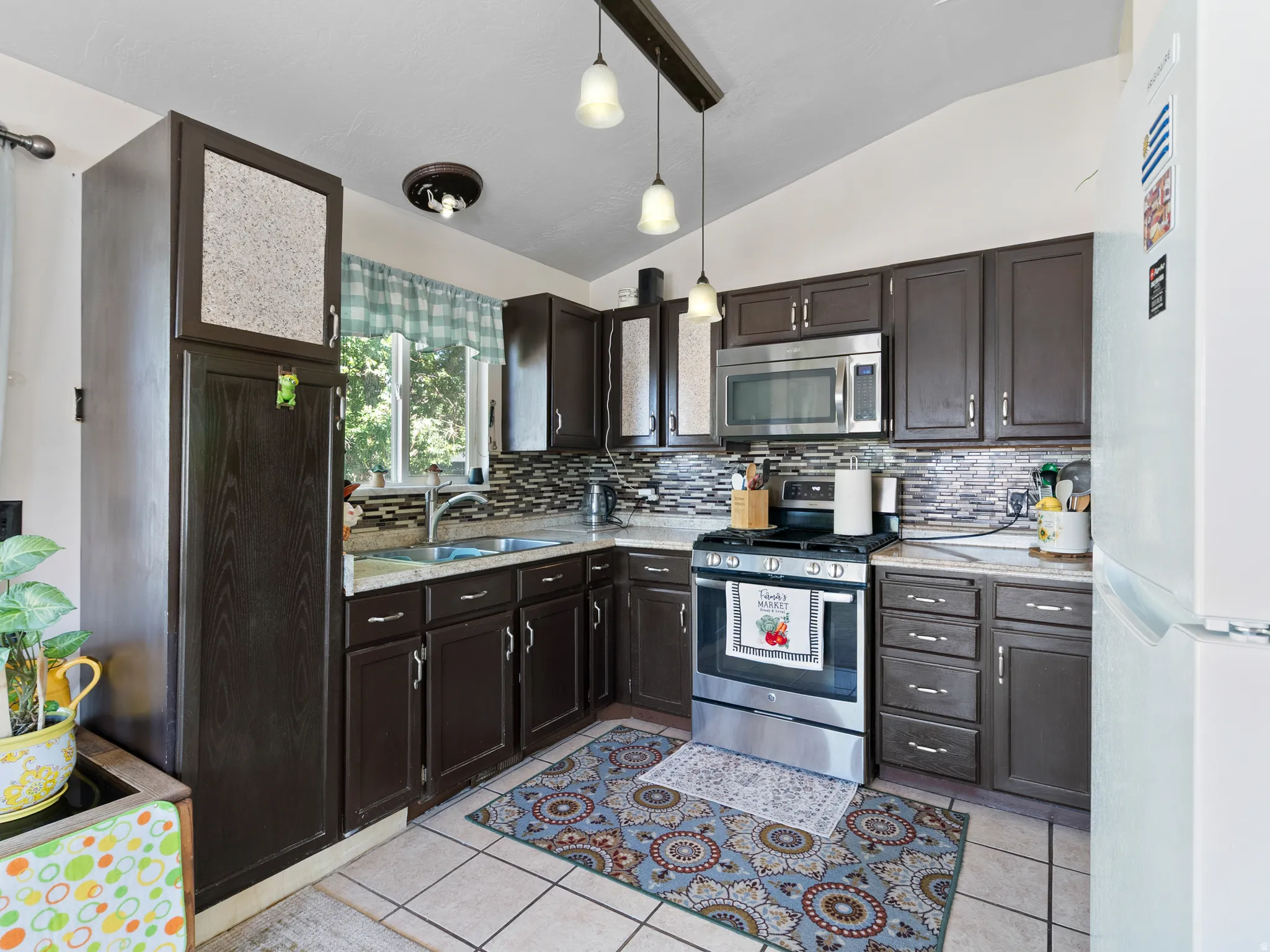 Kitchen featuring dark wood-finish cabinetry, a patterned tile backsplash, and light-toned countertops