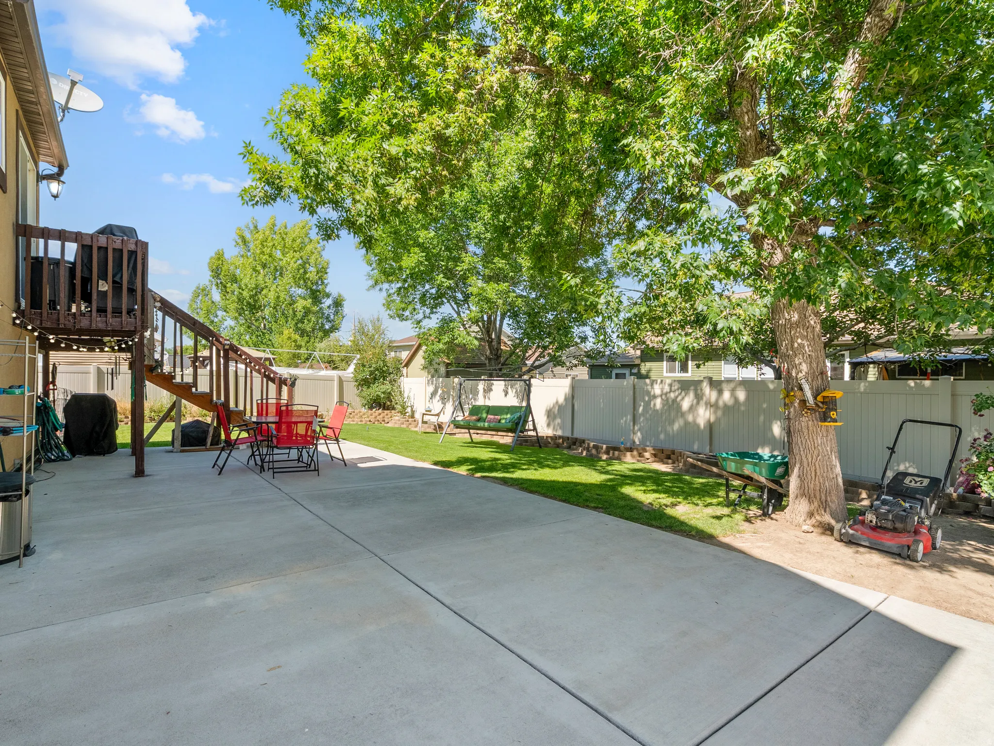 Expansive concrete patio with a tiered wooden deck featuring railings