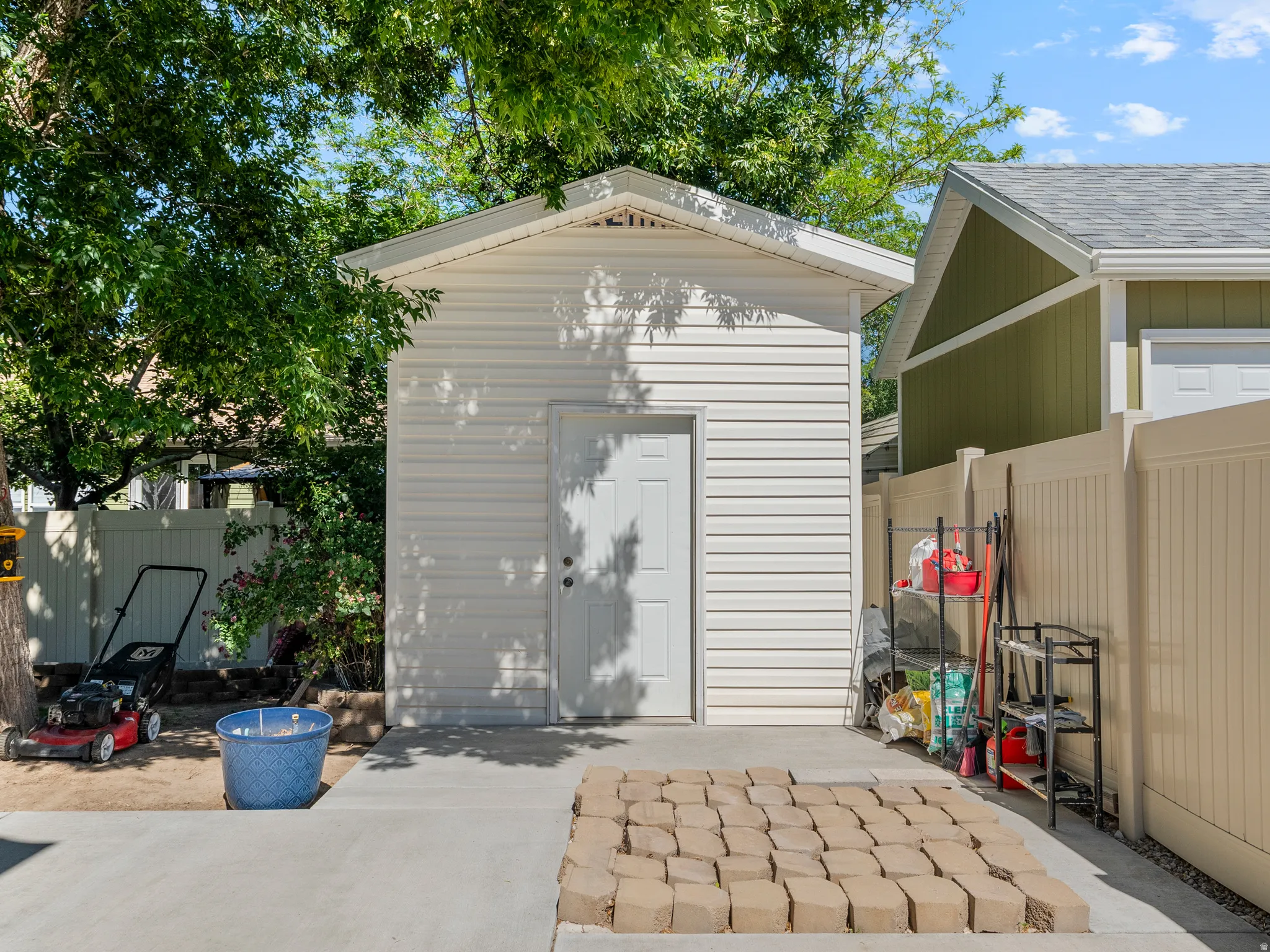 Detached white vinyl siding shed with a single entry door and a gable roof