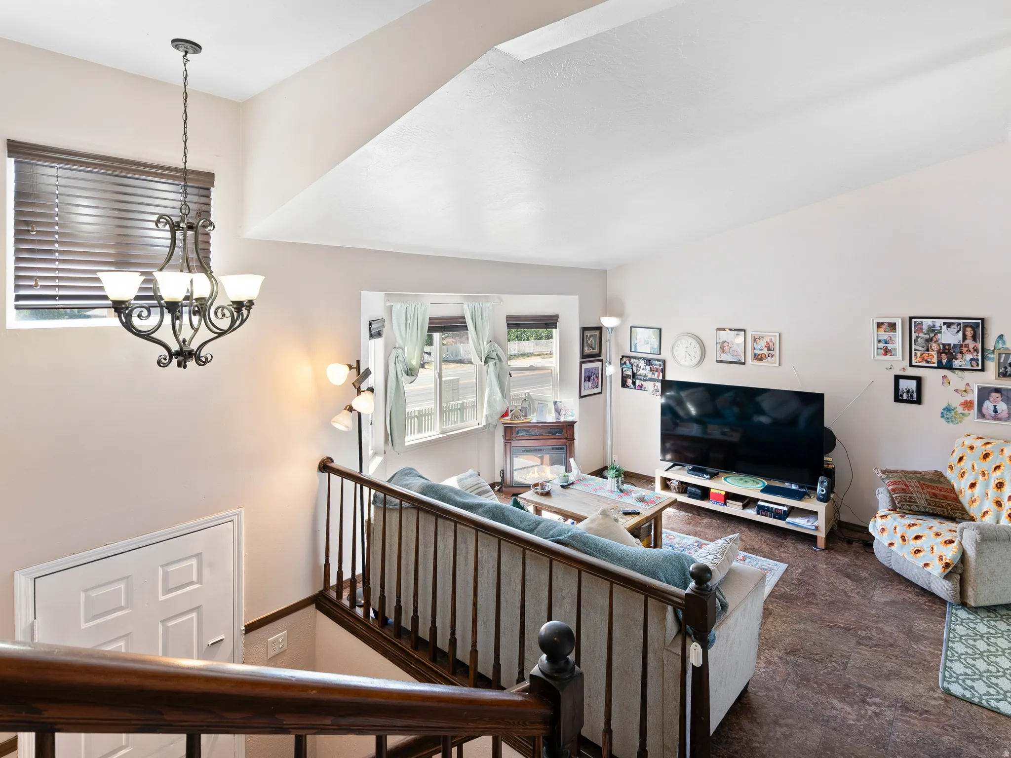 Open living area featuring vaulted ceilings, a decorative wrought iron chandelier, and wood-finish flooring