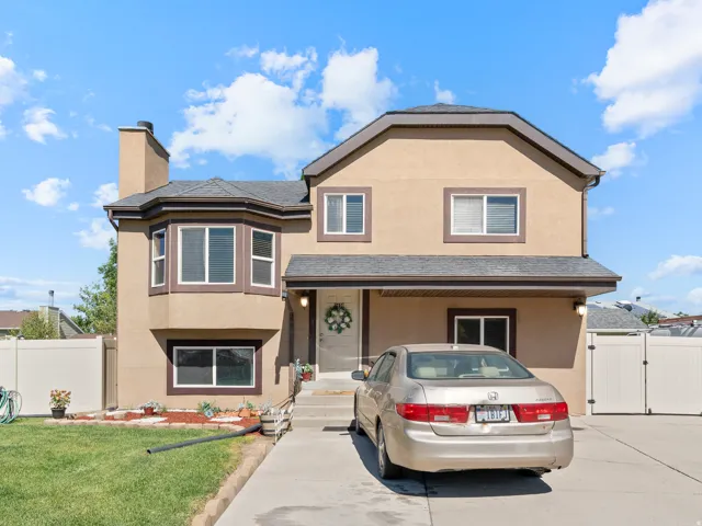 Stucco-sided residence featuring a prominent bay window, dark trim accents, and a covered entry