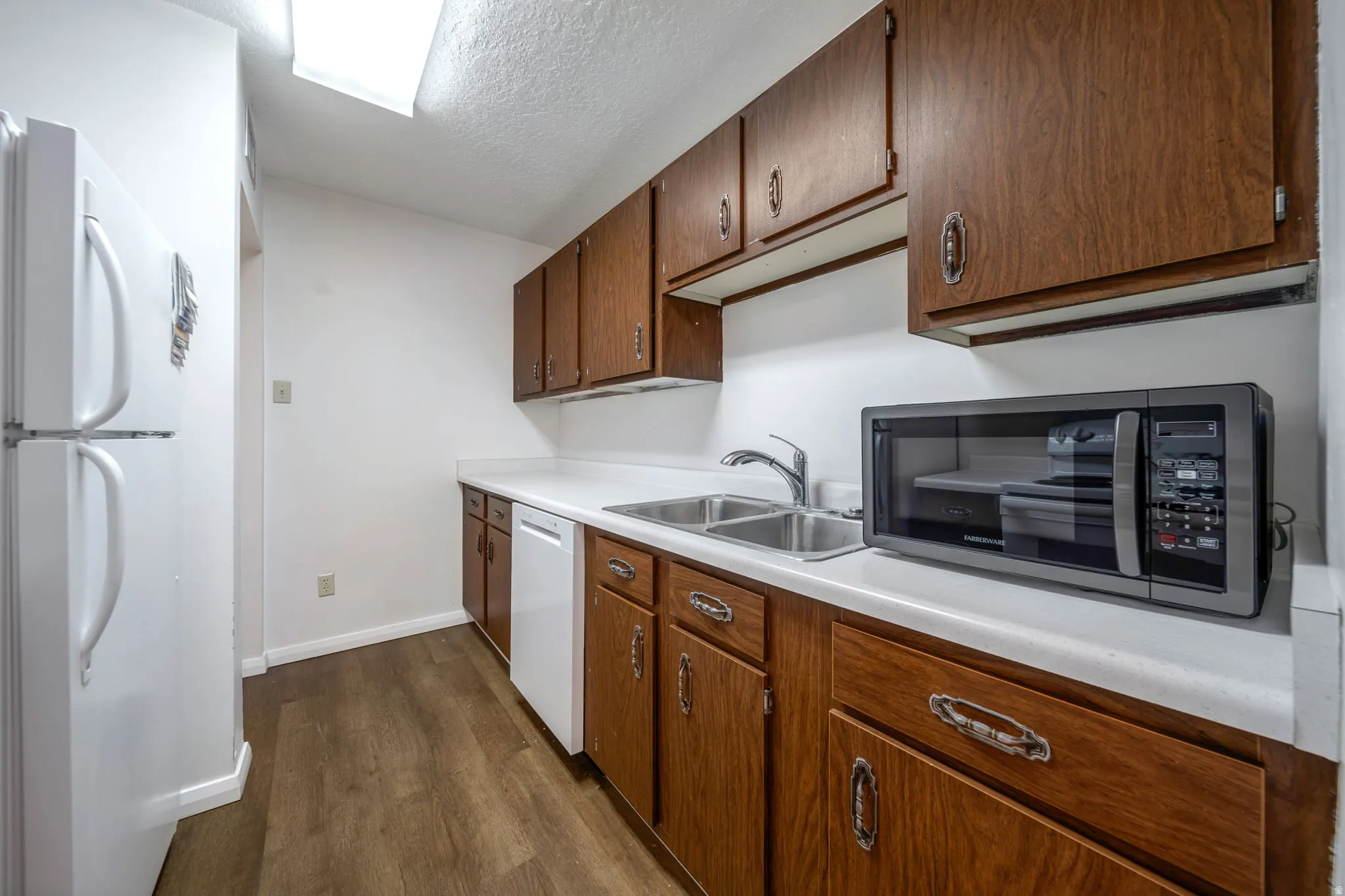 Kitchen featuring wood-finish cabinetry with silver hardware, white countertops, and wood-finish flooring