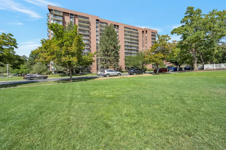 Expansive green space featuring mature trees and a multi-story residential building with private balconies
