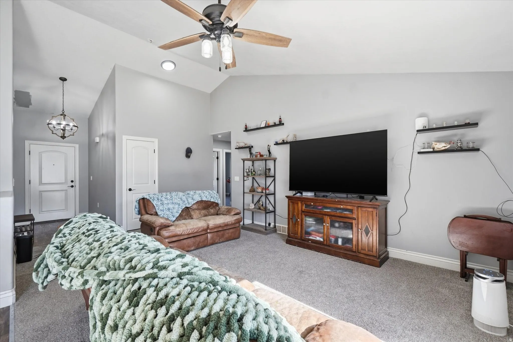 Living area featuring vaulted ceilings, a ceiling fan with integrated lighting, and gray carpeting