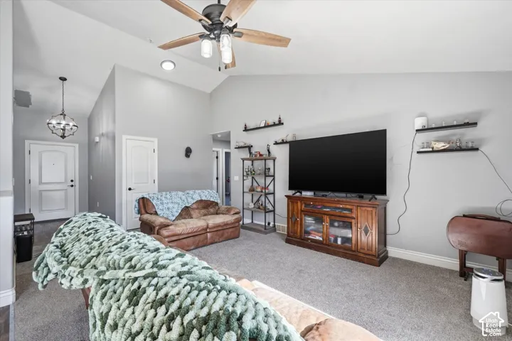 Living area featuring vaulted ceilings, a ceiling fan with integrated lighting, and gray carpeting