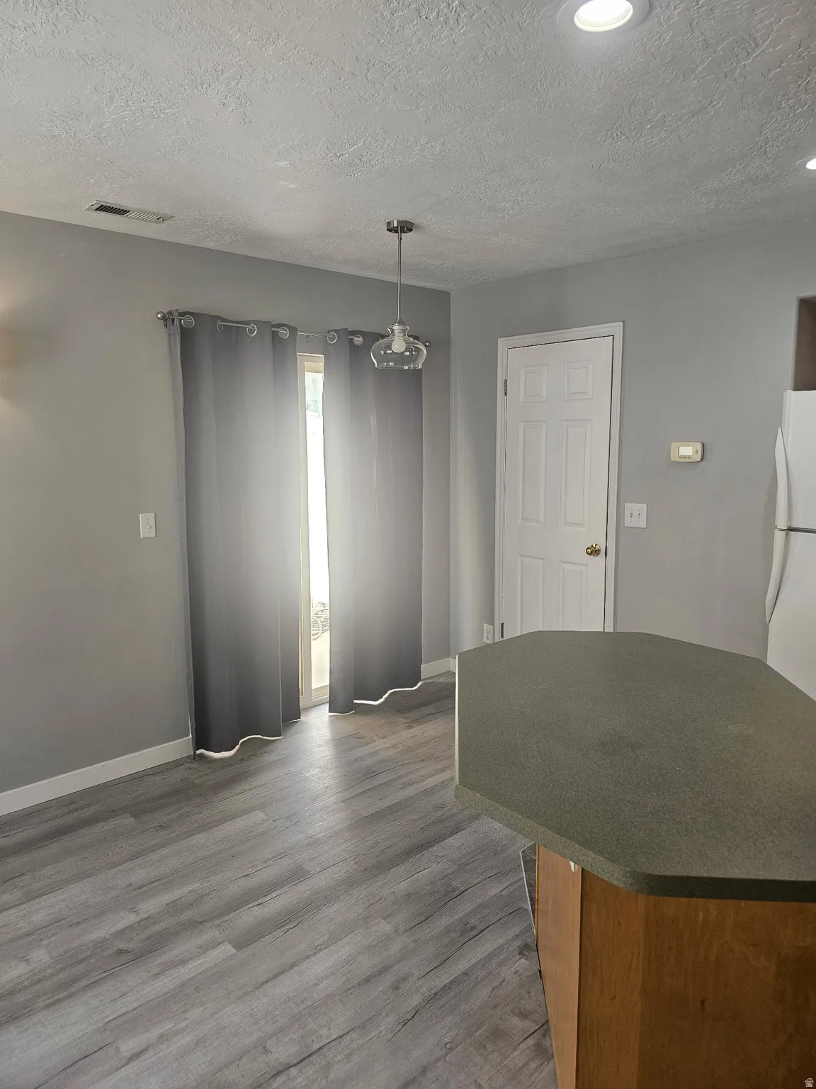 Wood-finish flooring throughout, modern pendant lighting, recessed ceiling lights, white trim, and a built-in island with countertop