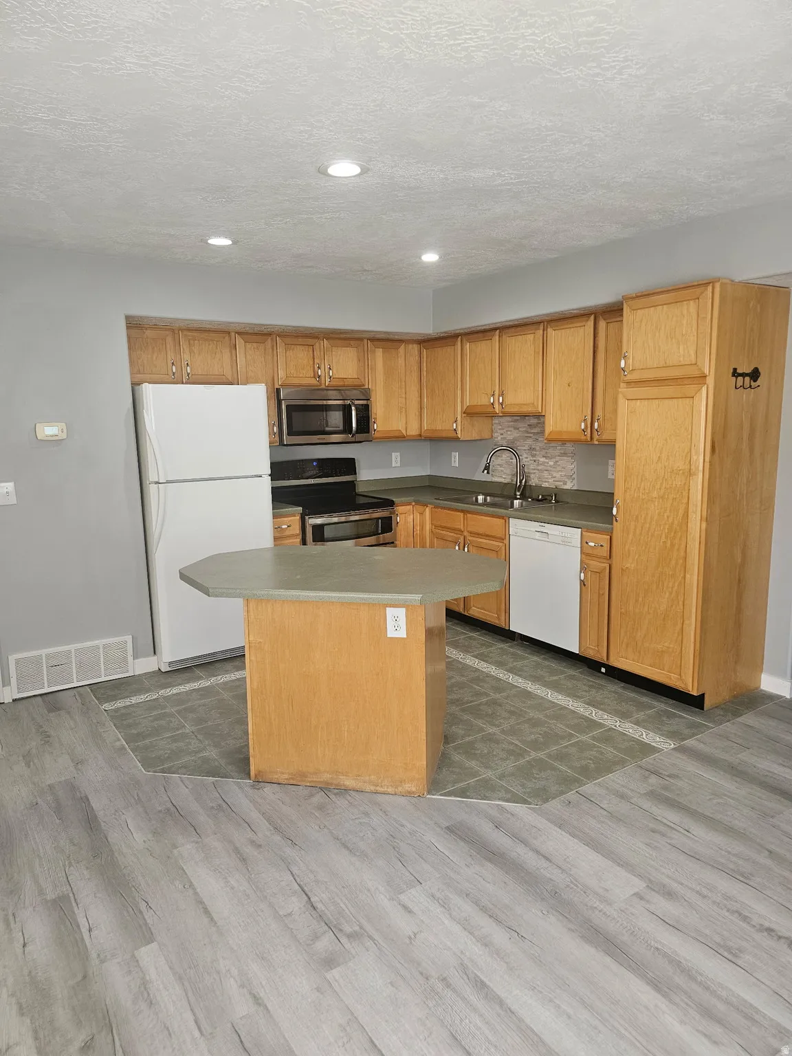 Kitchen featuring wood cabinetry, an island with countertop, and recessed lighting