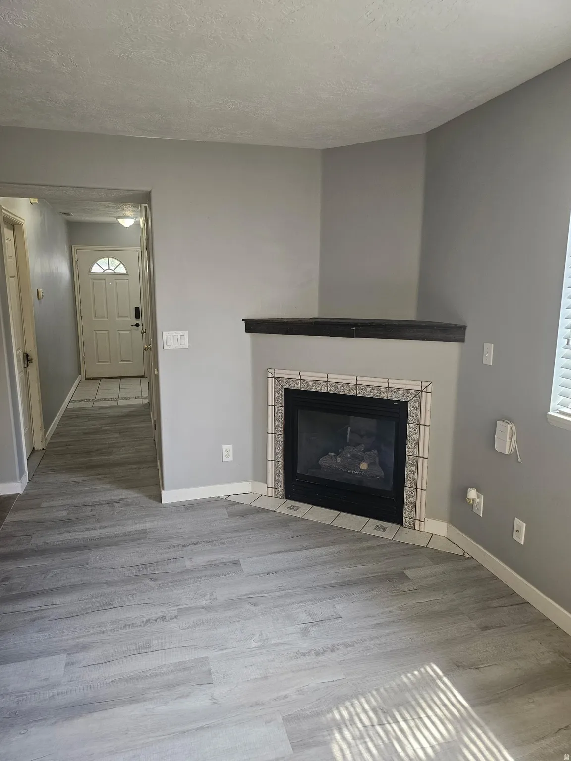 Corner fireplace with decorative tile surround and dark wood mantel