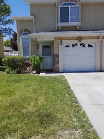 Stucco exterior featuring an arched window, a single-car garage, and a concrete driveway
