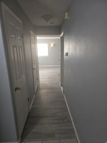 Hallway featuring wood-finish flooring, light gray wall paint, and white paneled doors