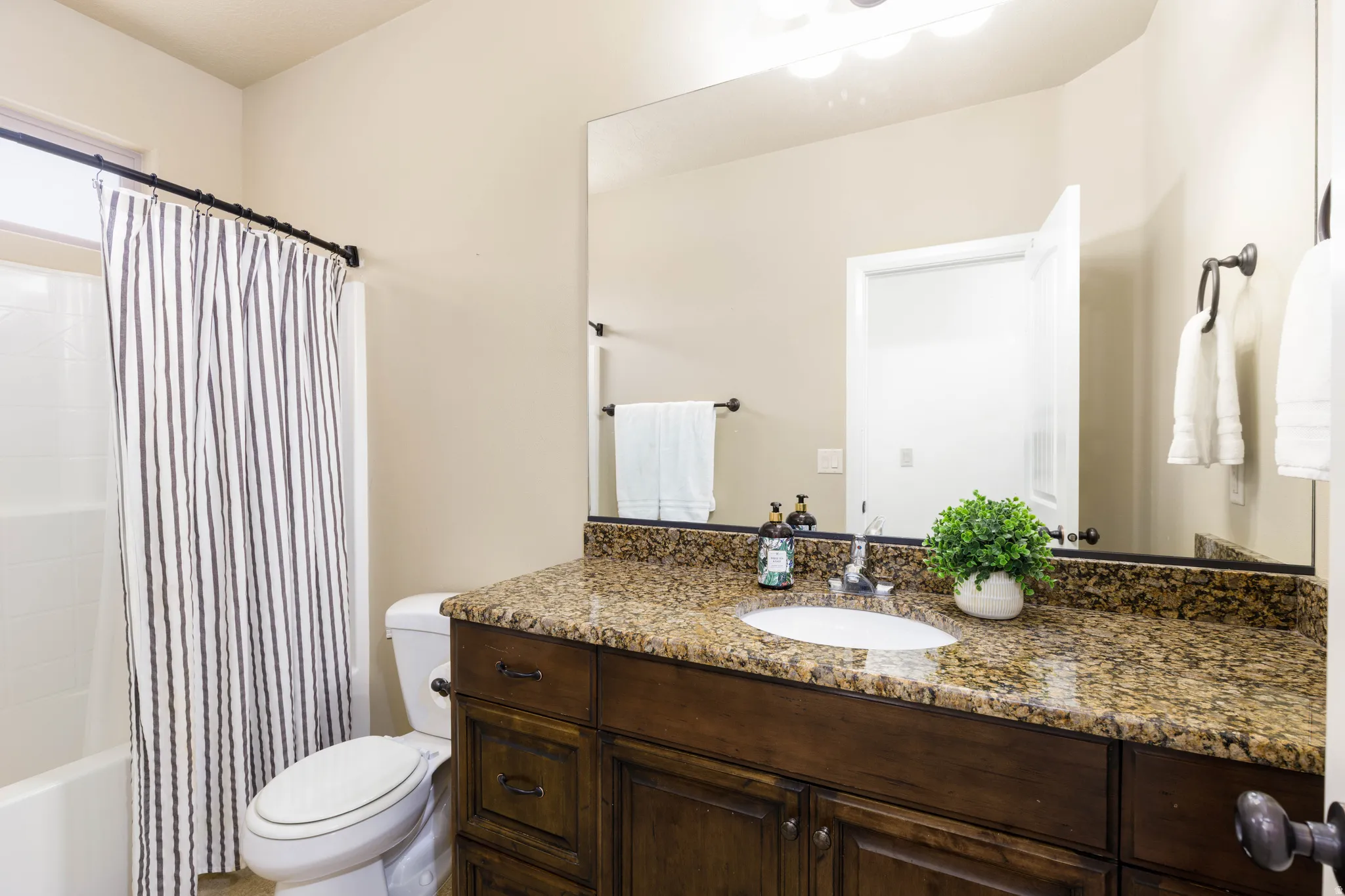 Guest bathroom featuring a wood-finish vanity with a granite-style countertop and an undermount sink
