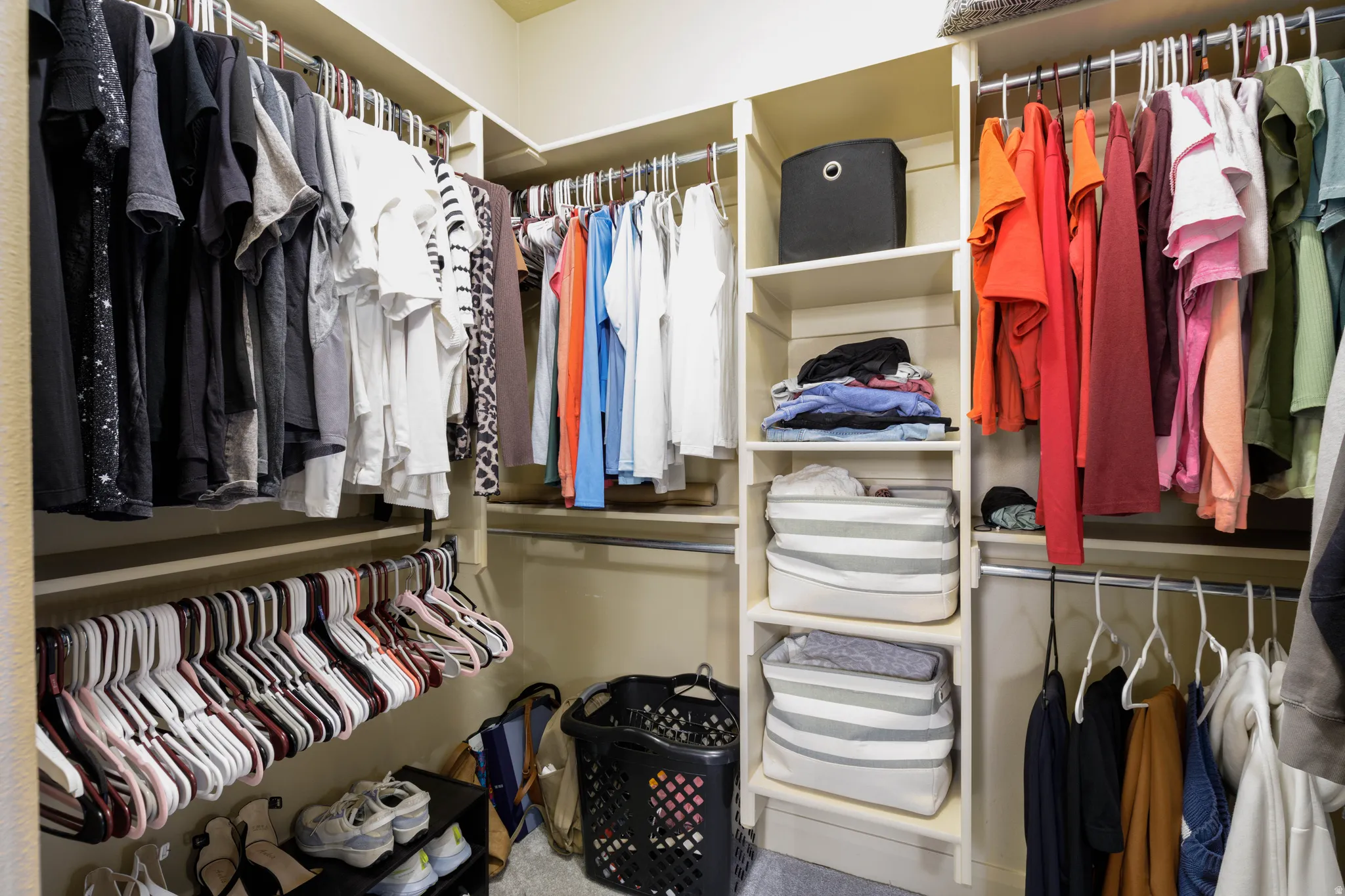 Primary suite walk-in closet featuring built-in shelving, multiple hanging rods, and integrated shoe storage