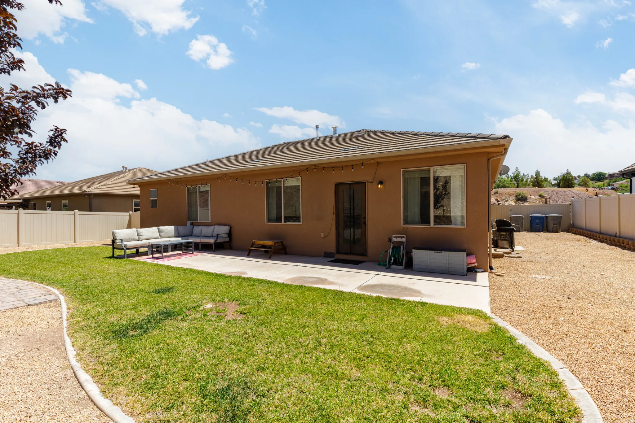 Expansive backyard featuring a combination of manicured lawn, gravel landscaping, and a concrete patio