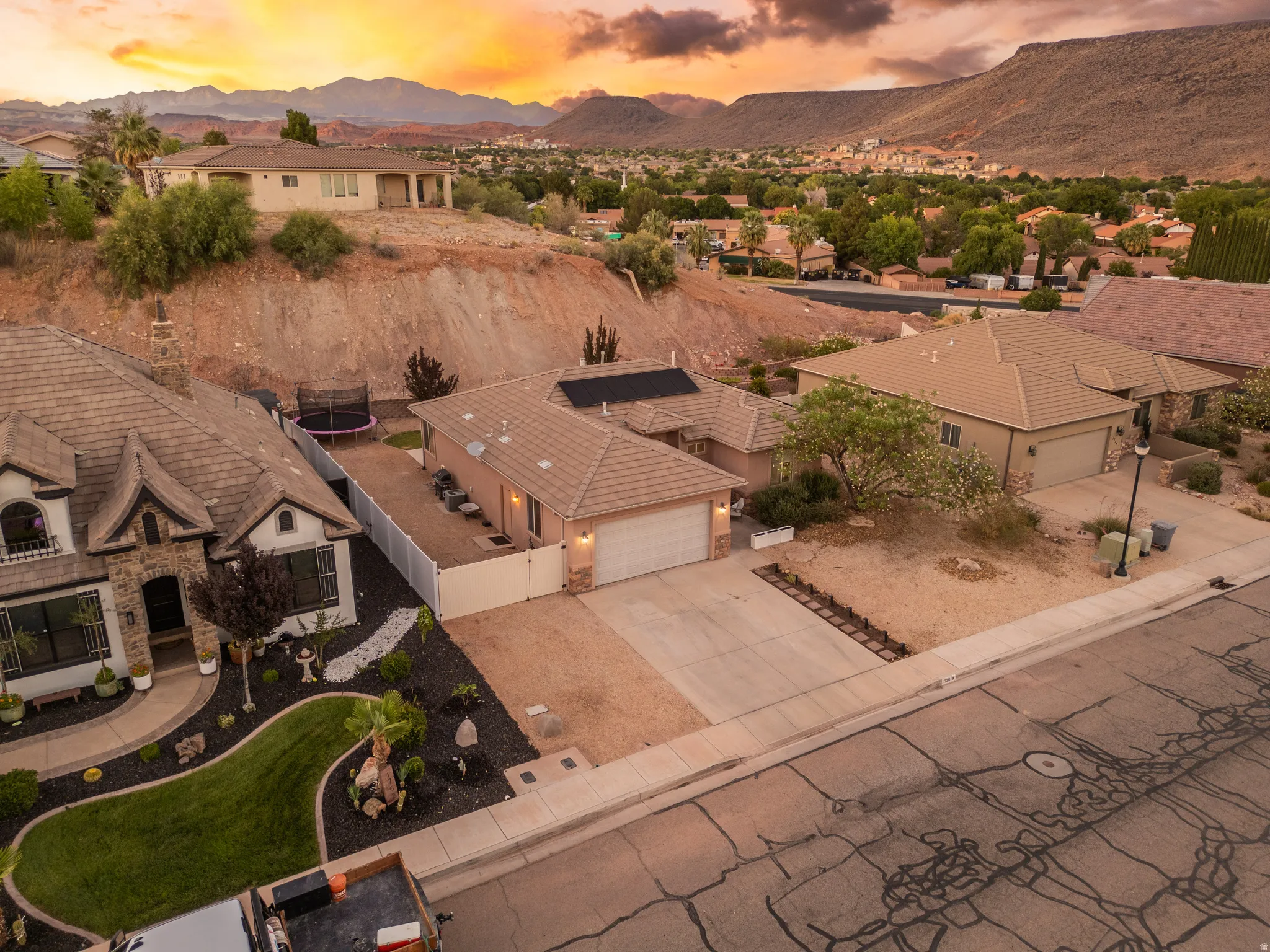 Residential property featuring a stucco exterior with a two-car garage, mature landscaping, and a fenced yard