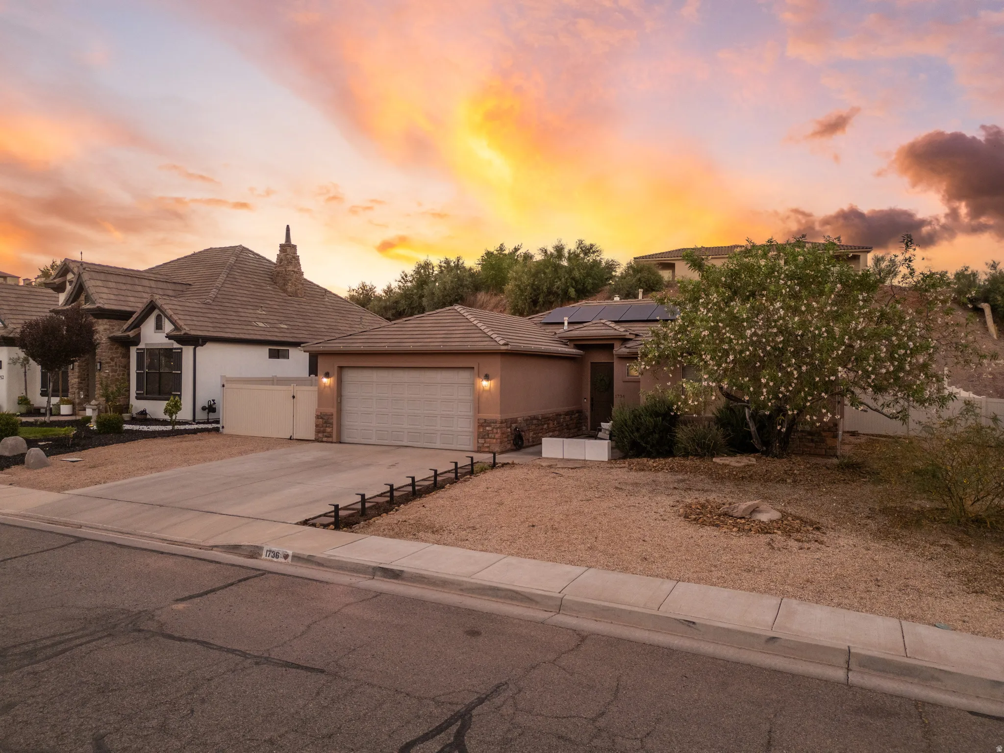 Contemporary stucco exterior with a tiled roof, integrated two-car garage, and a concrete driveway