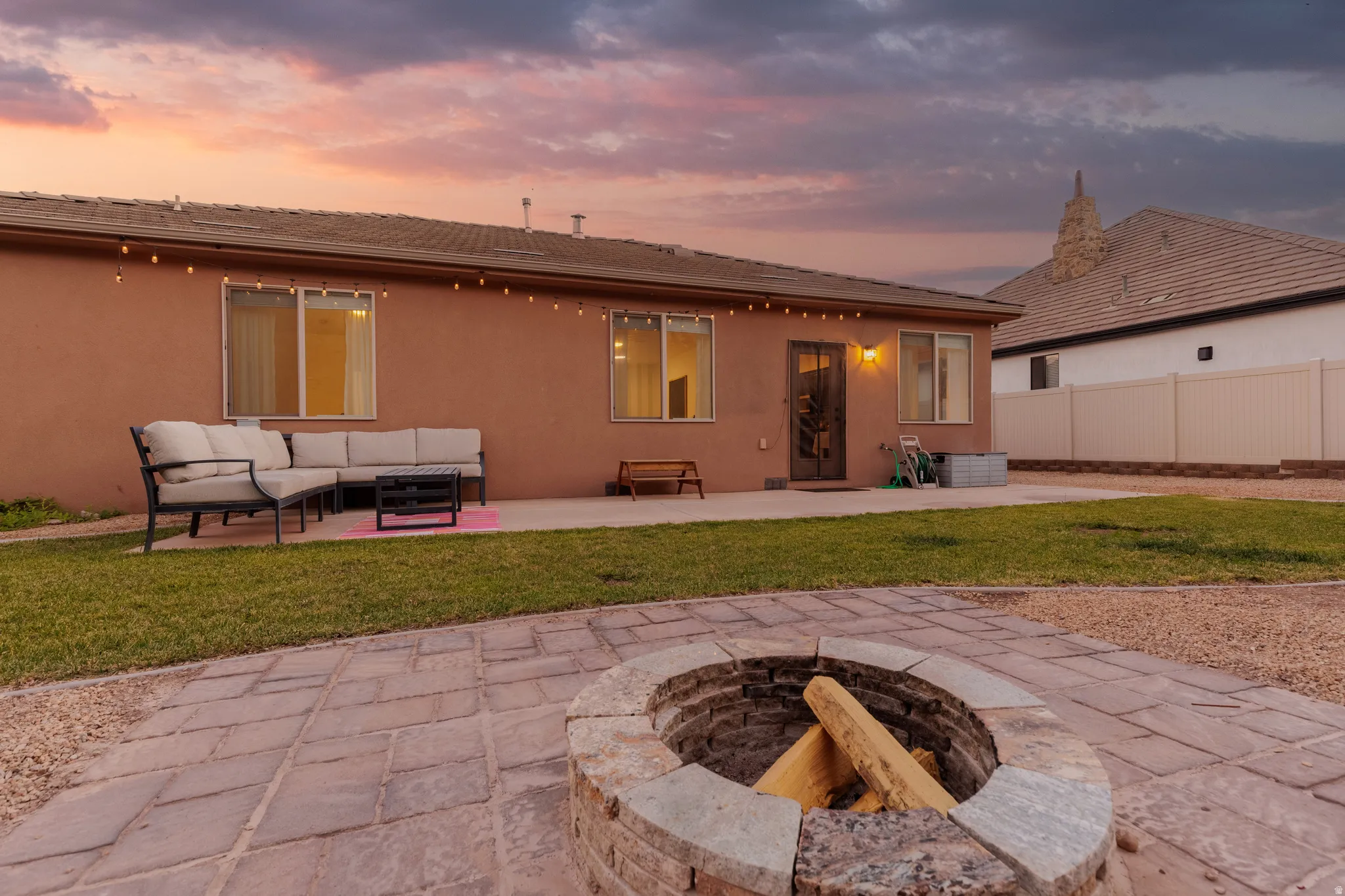 Stone fire pit with a paver patio and string lighting