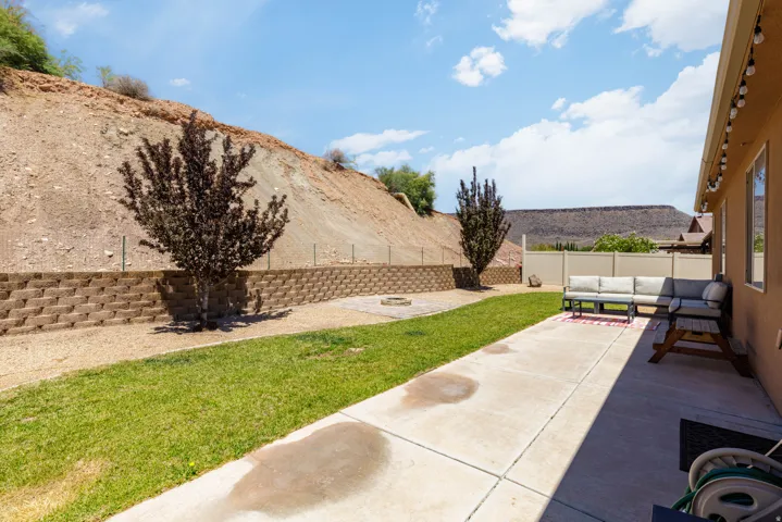 Expansive backyard featuring a concrete patio, green lawn, and terraced retaining wall