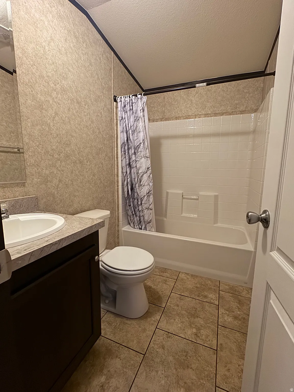 Full bathroom featuring a white drop-in bathtub with a tile surround, a white toilet, and a vanity with a white oval sink