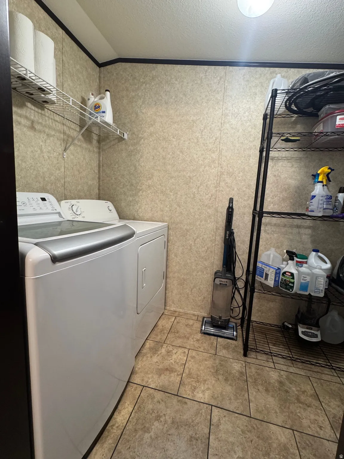 Utility space featuring durable tile flooring, a built-in wire shelf, and a freestanding storage rack