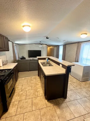 Kitchen featuring dark wood-finish cabinetry, light-toned countertops, and a stainless steel double sink