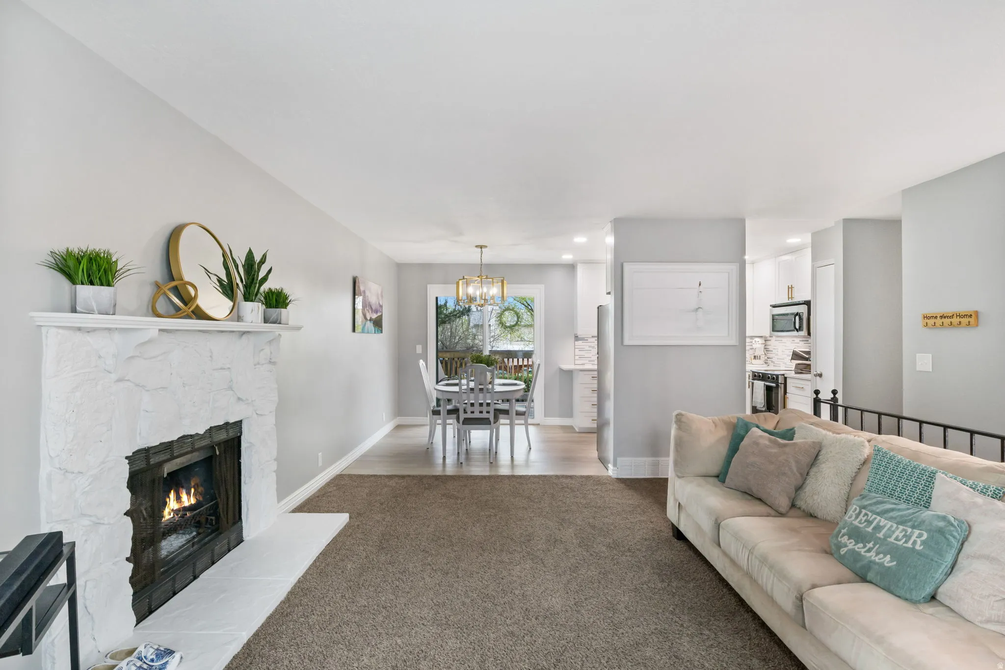 Living area featuring a stone-clad fireplace with a hearth, carpeted flooring, and light gray wall finishes