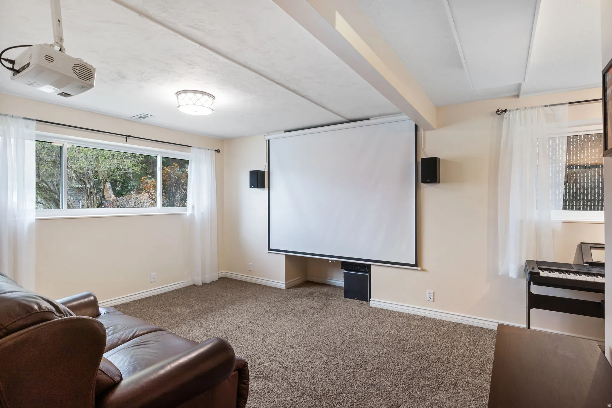 Dedicated media room featuring a ceiling-mounted projector and a large retractable screen