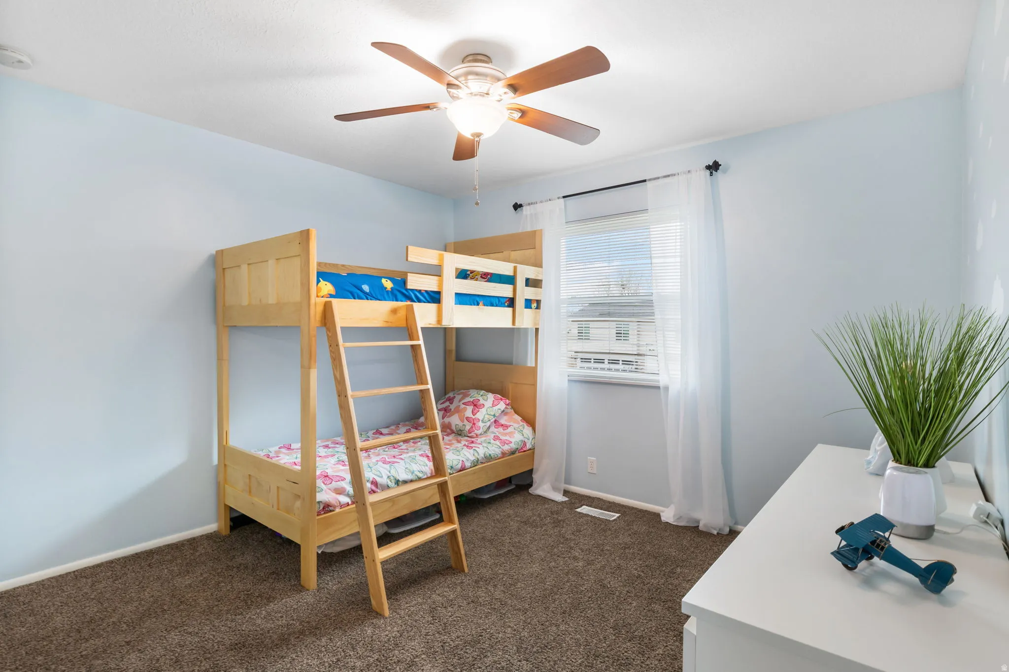 Bedroom featuring carpet flooring, a ceiling fan, light blue walls, and a window with blinds