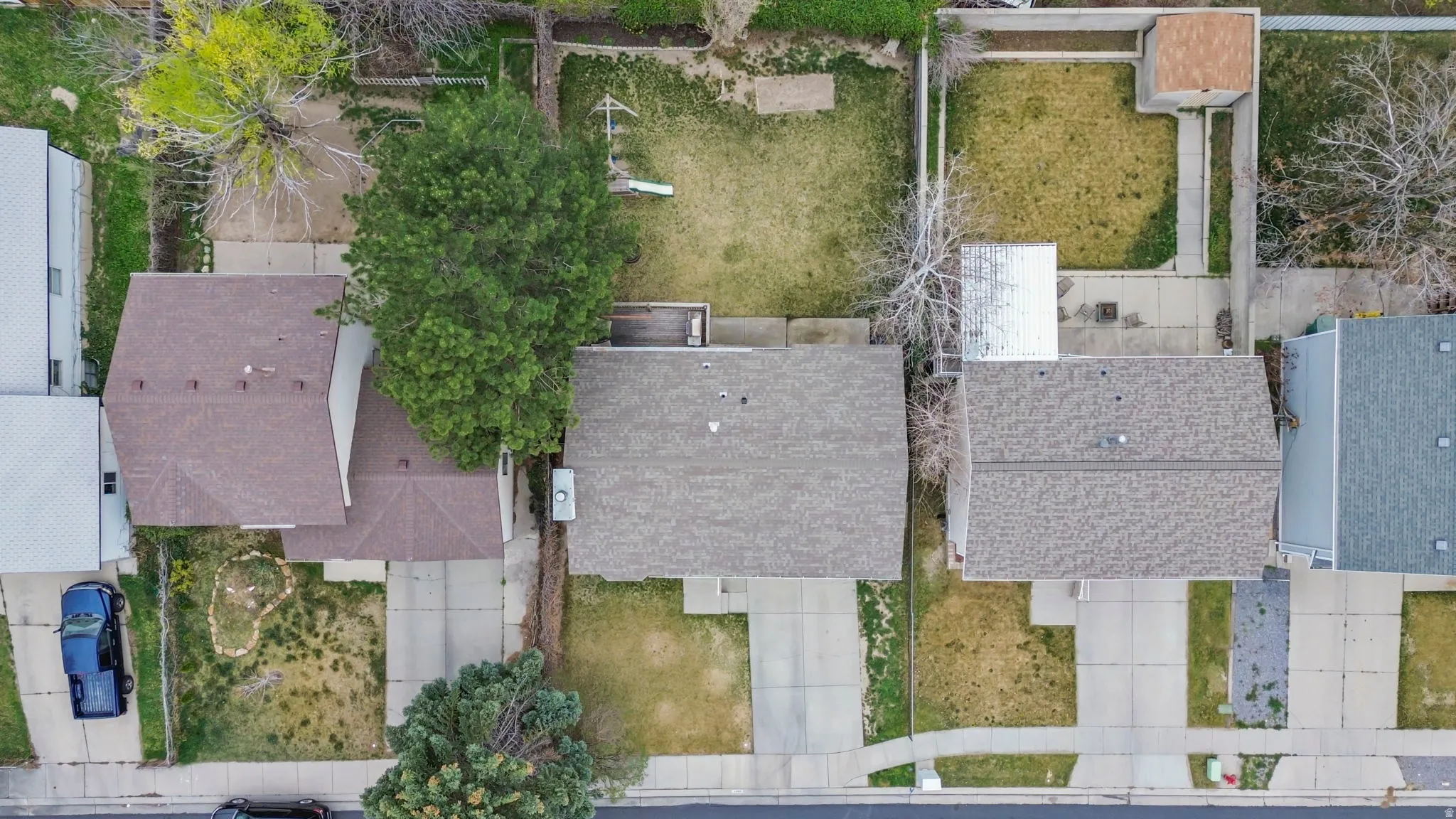 Property featuring a brown shingle roof, a concrete driveway, a concrete patio, and a detached shed