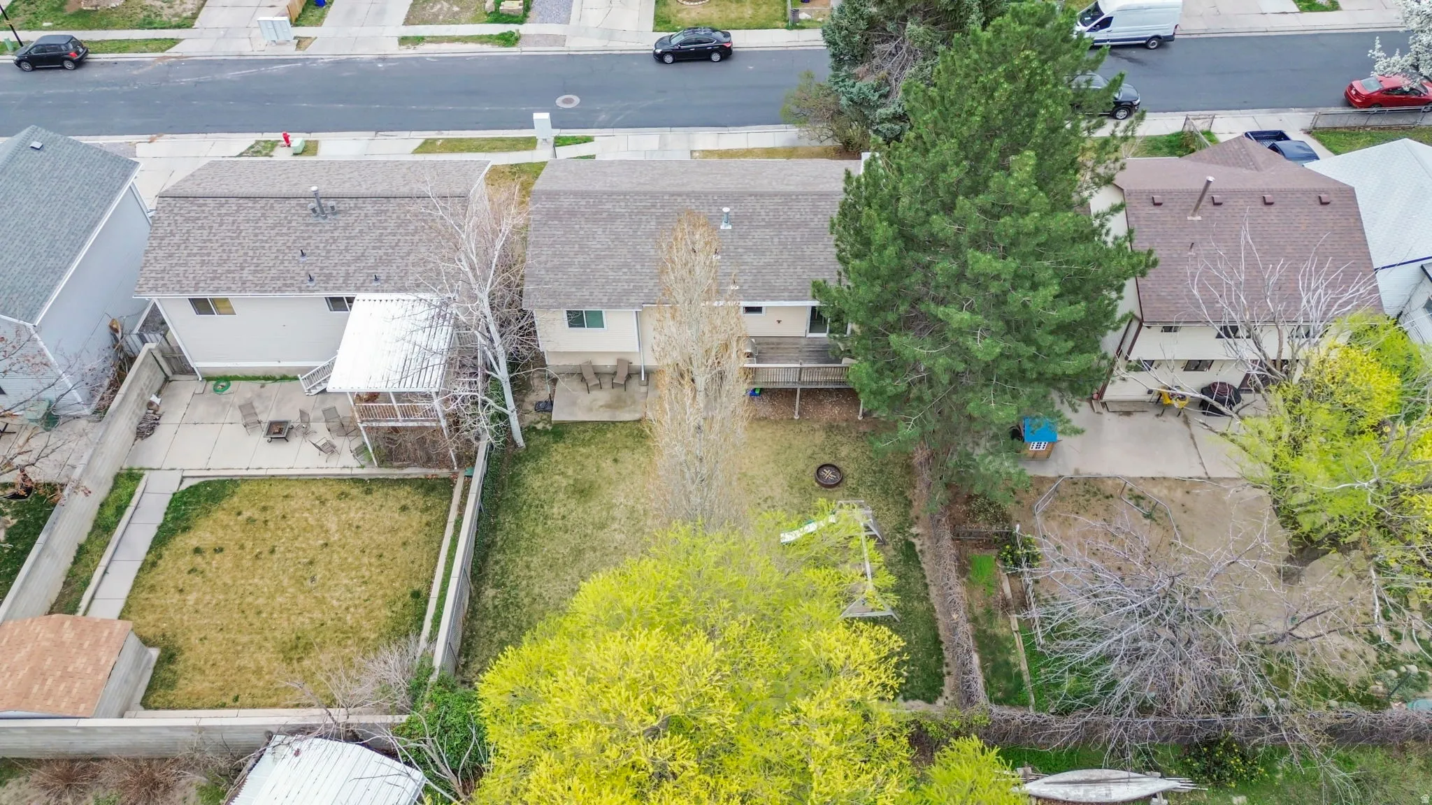 Expansive backyard featuring a manicured lawn, concrete patio, and mature trees