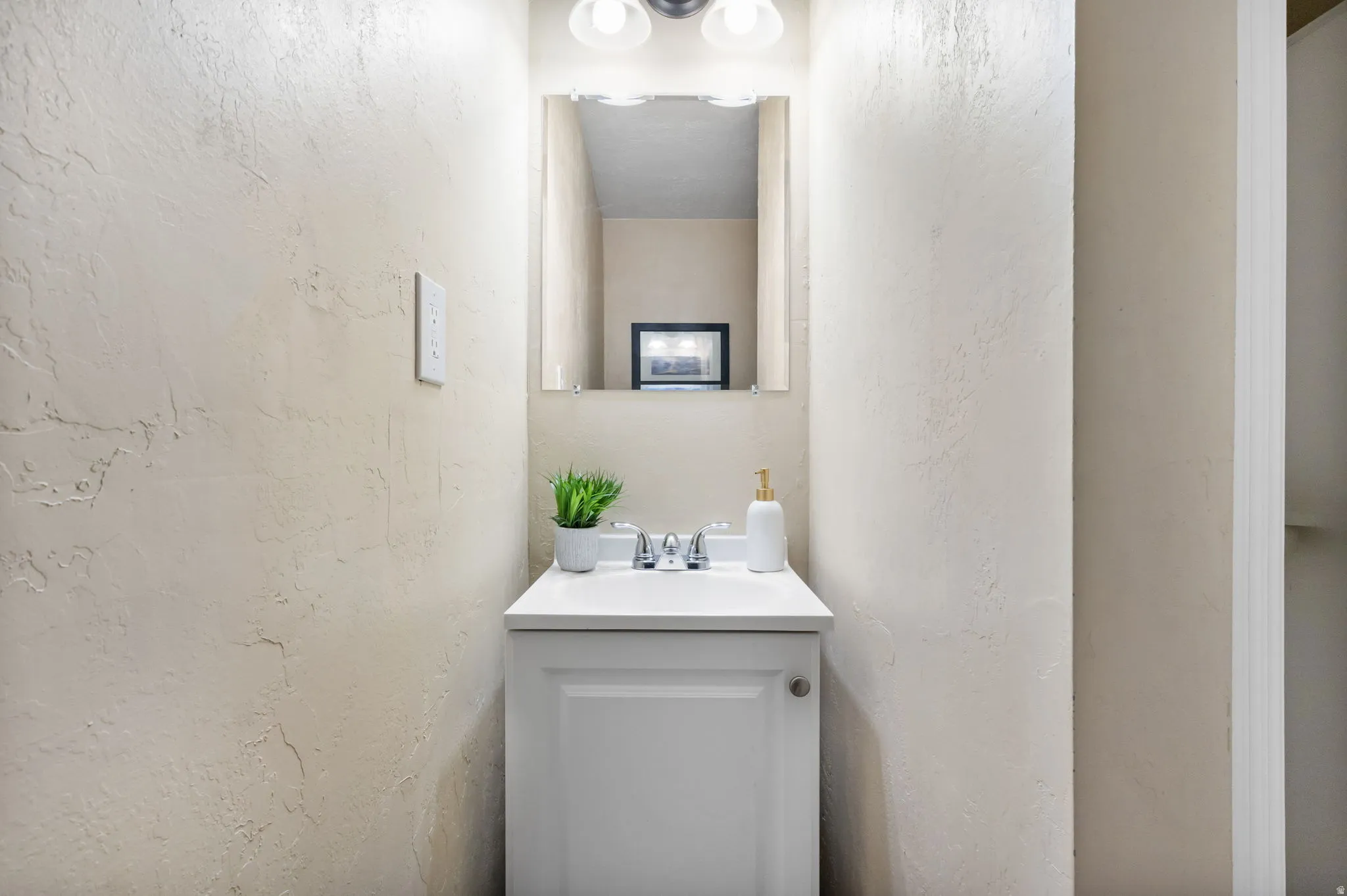 Vanity with a white cabinet, white countertop, and chrome faucet